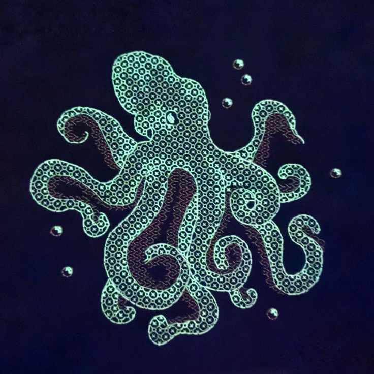 Completed cross-stitch of an octopus highlighting the glow in the dark thread that was used