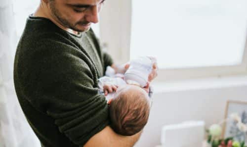 Adoptive dad feeding his baby boy a bottle