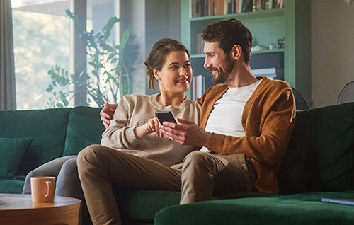 Couple looking at a text from their adoption agency from their sofa