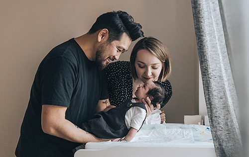 Young couple admiring their newborn baby after changing his diaper