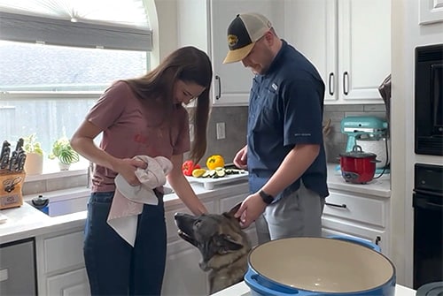 Beverly and Michael pause in their kitchen to pet one of their dogs