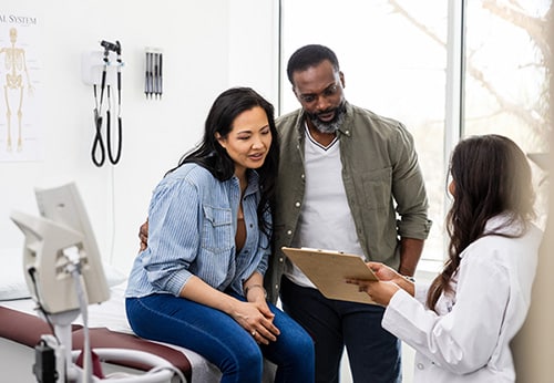 Female fertility doctor speaks with a couple in her office