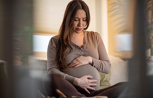 Pregnant woman seated in her living room experiencing early labor pains