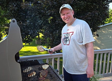 Hopeful adoptive dad Josh smiling for the camera as he grills meat