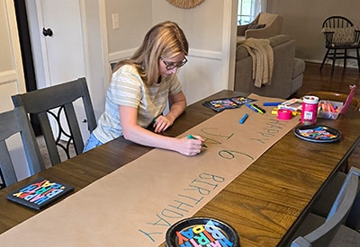 Rachel designing a banner for her son's 6th birthday