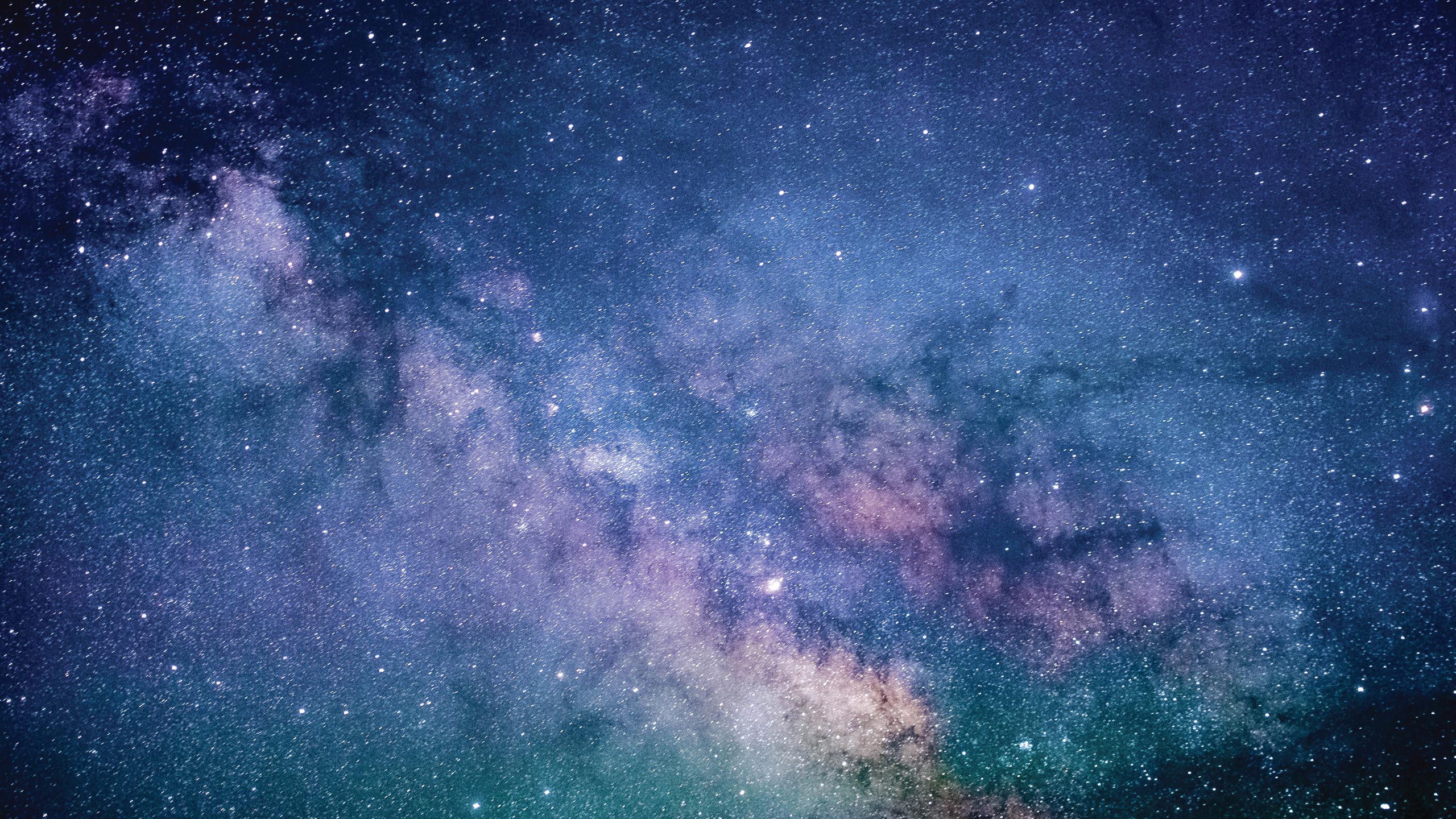 A stunning view of the night sky filled with numerous stars and distant galaxies. The image showcases a mix of colors, including shades of blue, purple, and pink, creating a mesmerizing cosmic tapestry.