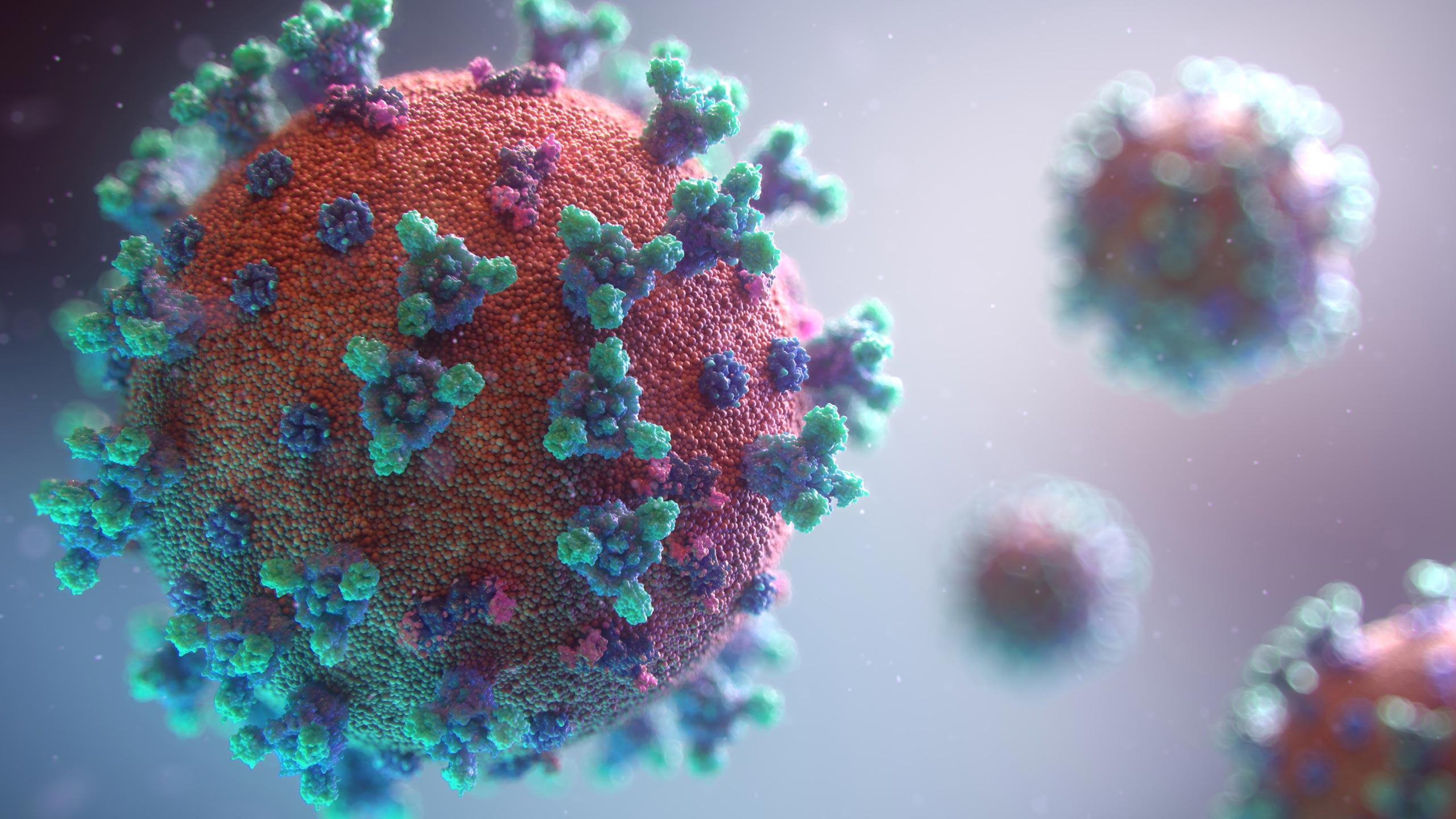 A detailed close-up 3D rendering of a virus particle, prominently featuring a spherical shape with a textured, orange surface. The surface is covered with blue and green spike-like structures. Blurry background shows additional similar particles.