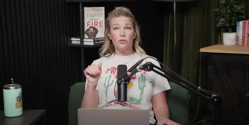 Woman in a podcast studio sits at a green chair, speaking into a microphone with a laptop in front.
