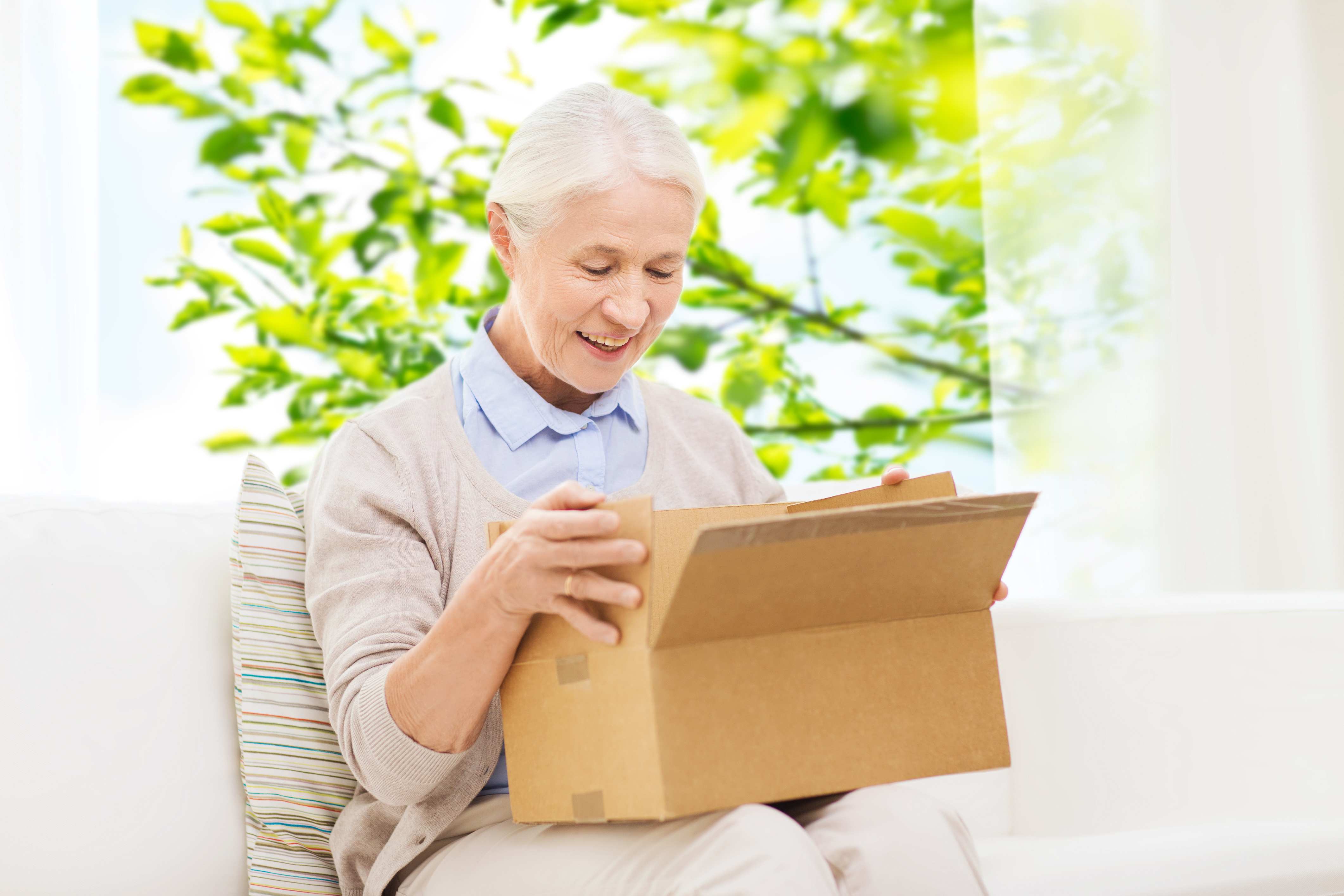 Ältere Dame mit geöffneter Box, sie schaut lächelnd in die Box.