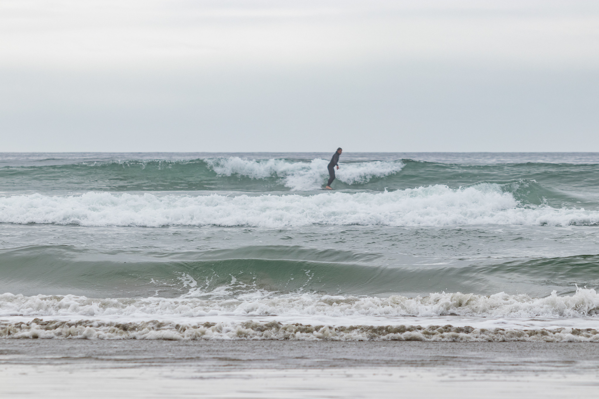 A surfer rides a wave on Vancouver Island, Canada