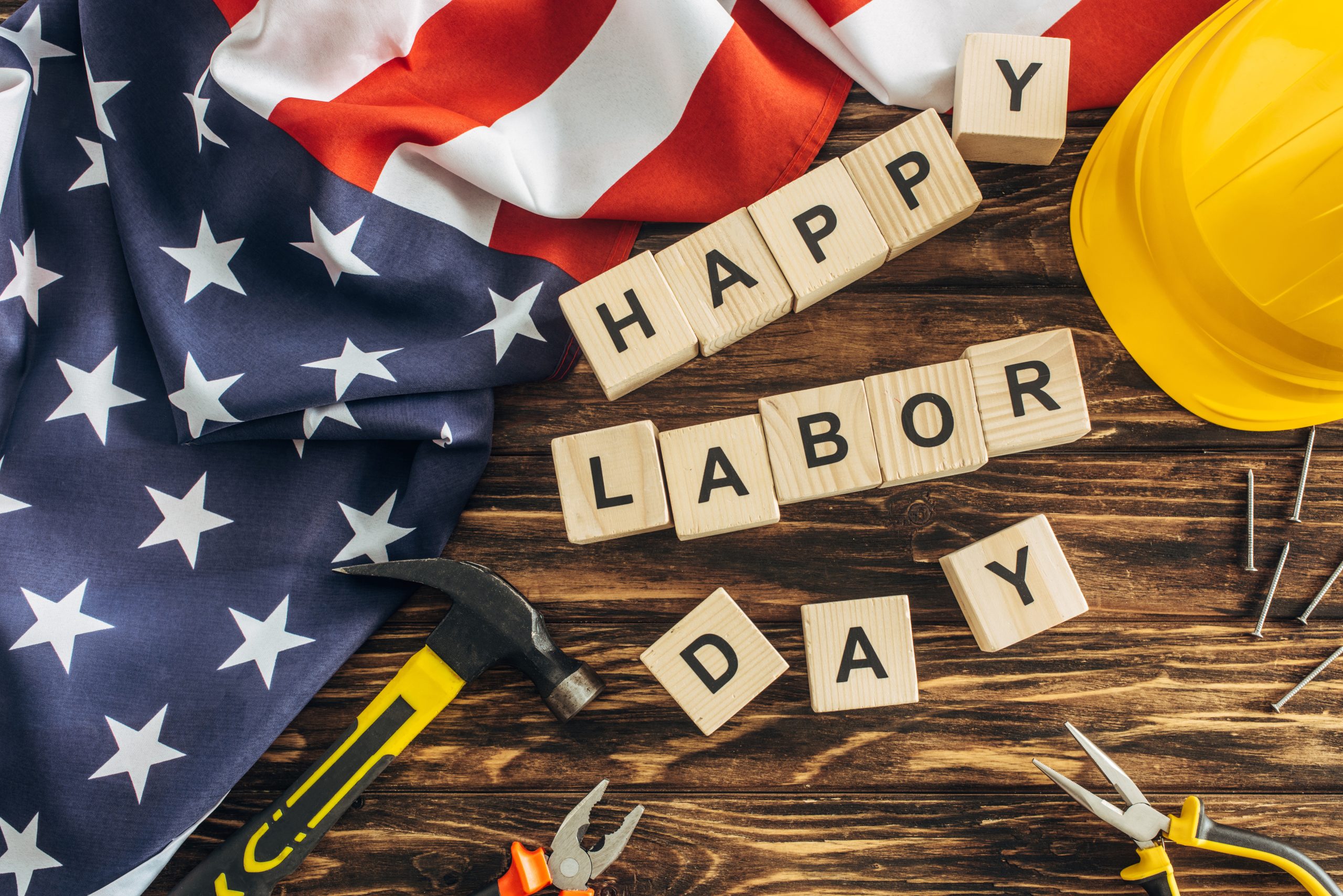 labor day lettering against a background of wood and an American flag