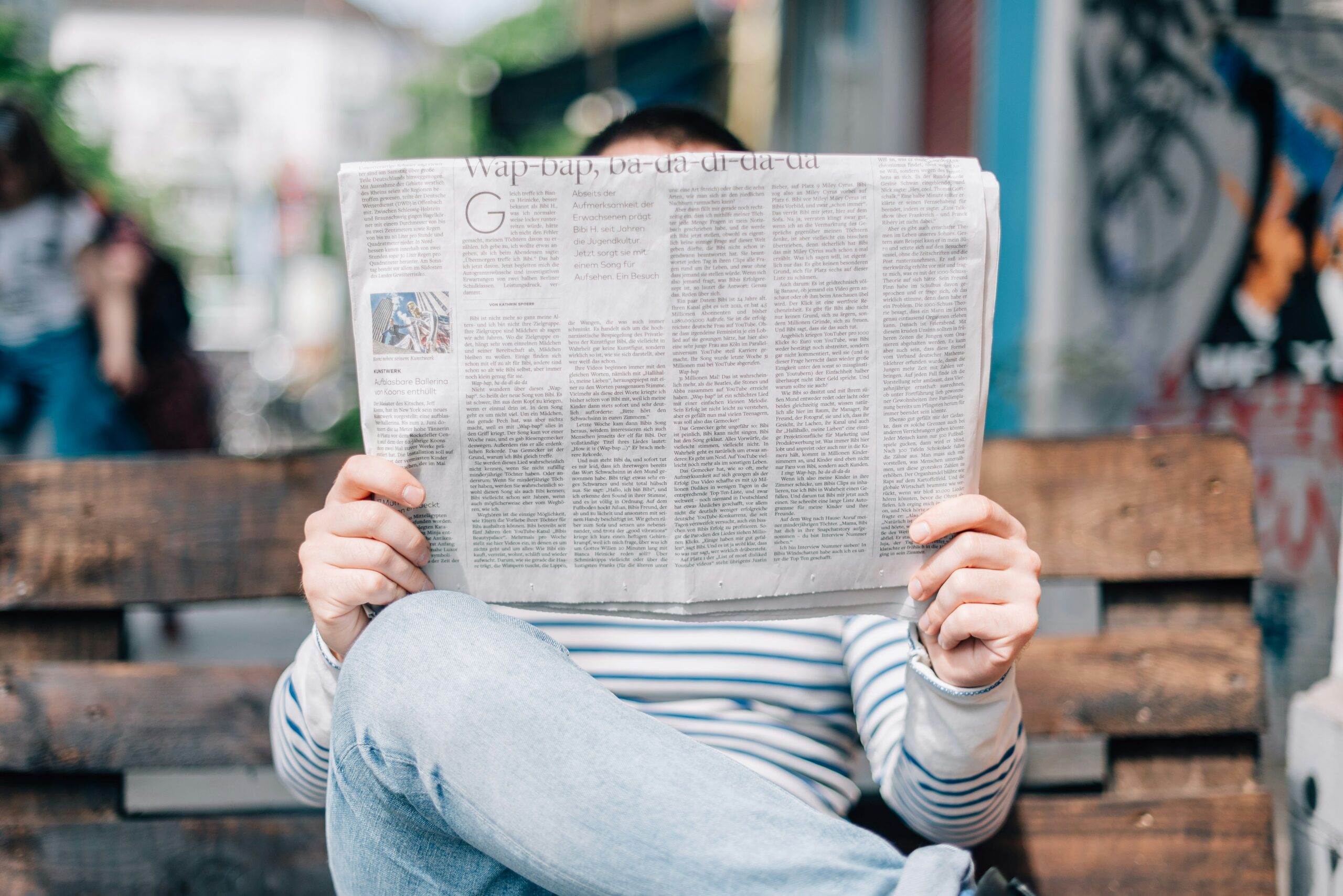 man reading newspaper on bench
