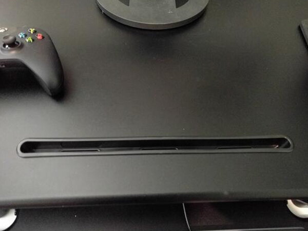 A game controller resting on the front slot built into the FlexiSpot desk surface