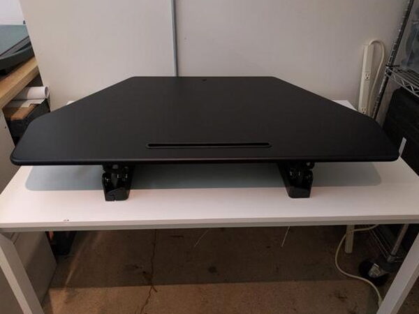 The FlexiSpot desk lowered to a seated working height, empty on top of a table