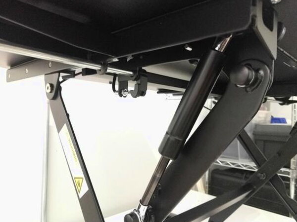 A close-up of the FlexiSpot desk's gas spring hovering mechanism underneath the platform