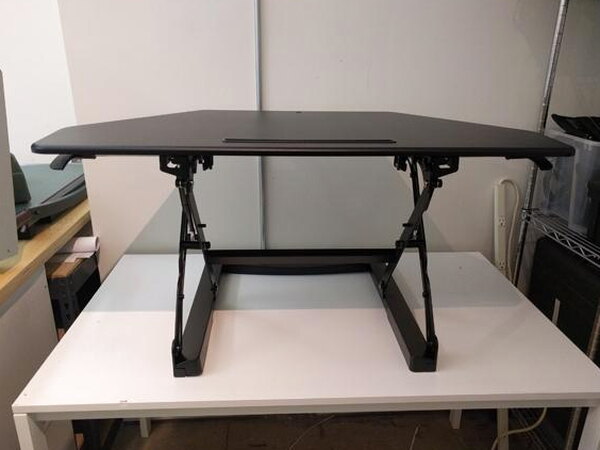 The FlexiSpot desk raised with a monitor, headset, keyboard, and mouse arranged on it