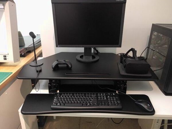 A hand gripping the height adjustment lever on the side of the FlexiSpot desk