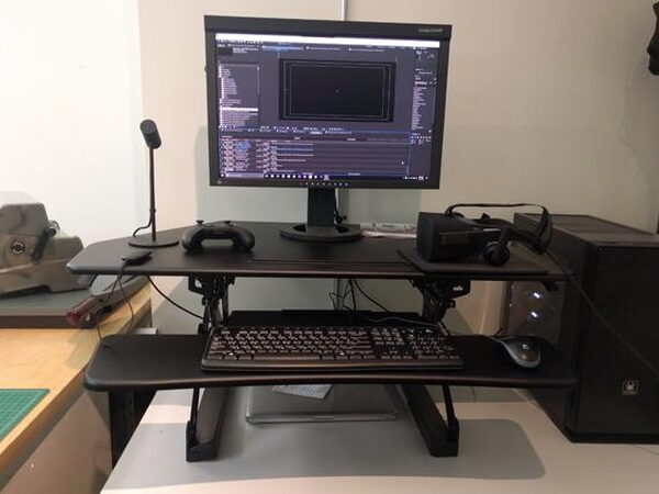 An editing timeline visible on a monitor sitting on the FlexiSpot desk