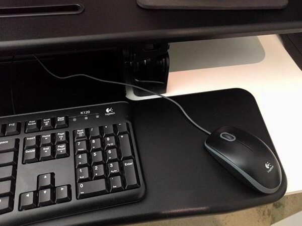 A keyboard and mouse resting on the FlexiSpot keyboard tray