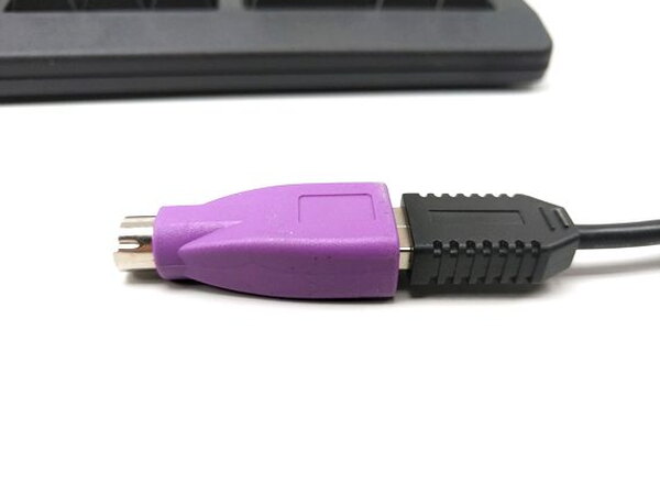 A close-up of the purple USB to PS/2 adapter attached to the keyboard's USB cable