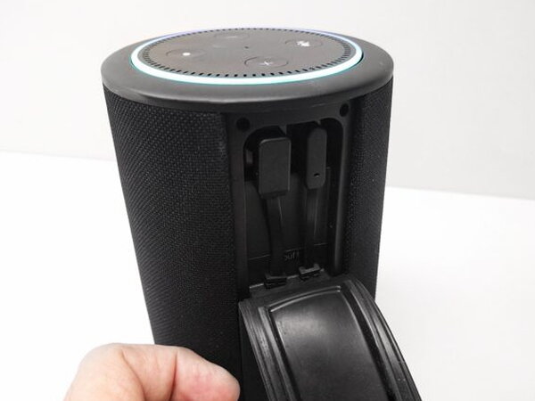 A hand closing the connector flap on the Vaux after seating the Echo Dot