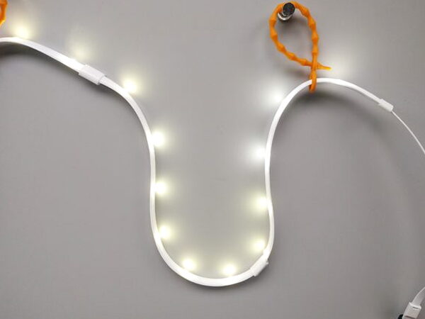 The Luminoodle light rope lit up in a curved shape with a mounting tie visible