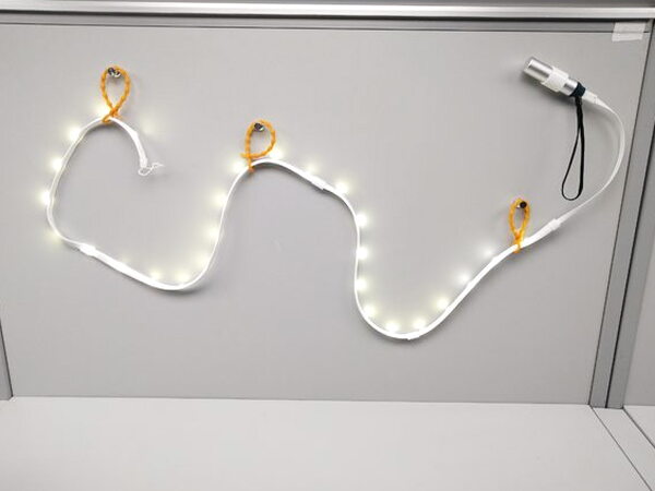 The Luminoodle light rope lit up and hung on a window frame with its mounting ties