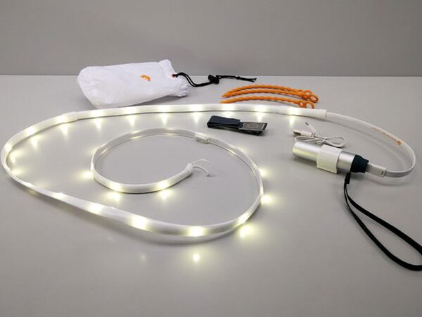 The full Luminoodle kit spread out on a table with the light rope coiled and lit