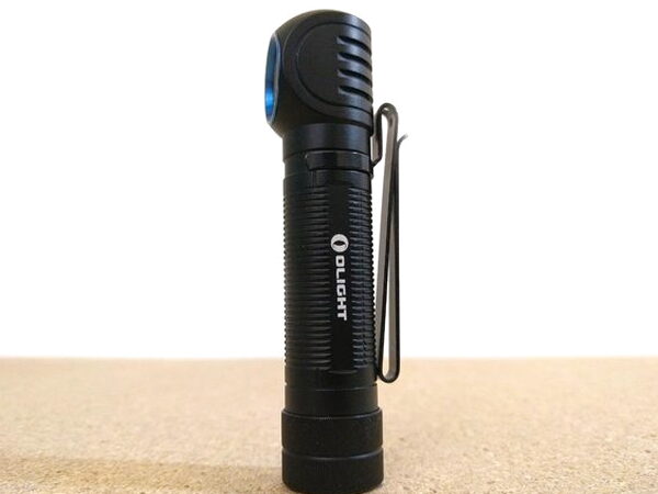 The Olight H2R Nova standing upright with its pocket clip attached