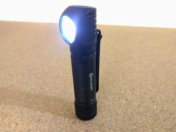 The Olight H2R Nova angled and lit up with its pocket clip still attached