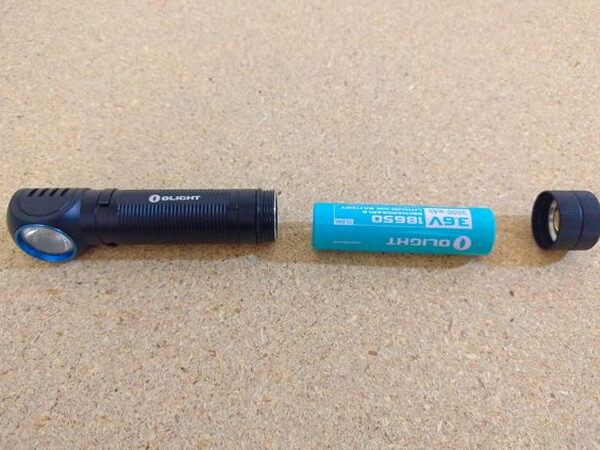 The Olight H2R Nova broken down into its three pieces: body, 18650 battery, and magnetic tailcap