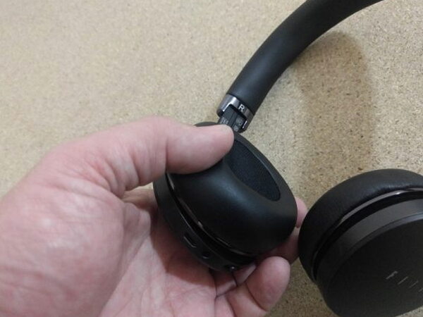 Adjusting the right earcup slider on the FIIL CANVIIS Pro with the R marking visible