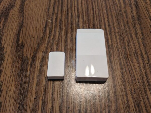 Two pieces of an Abode Mini Door/Window Sensor on a table