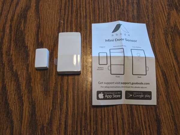 Abode Mini Door/Window Sensor pieces beside installation instructions