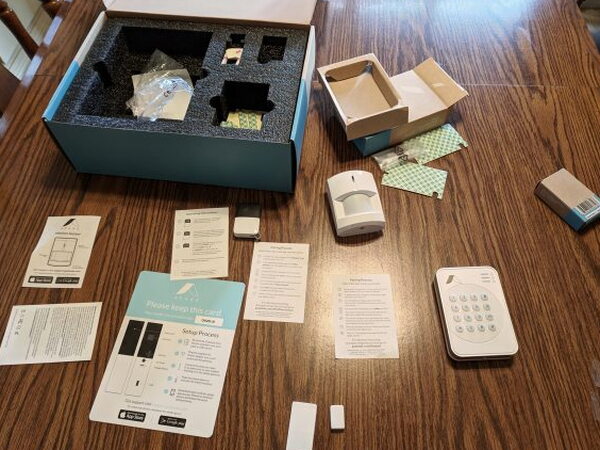 Abode packaging, manuals, keypad, sensors, motion detector, and gateway spread across a table