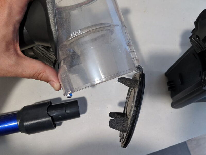 The lower dust bin latch opens so the collected debris can be dumped out.