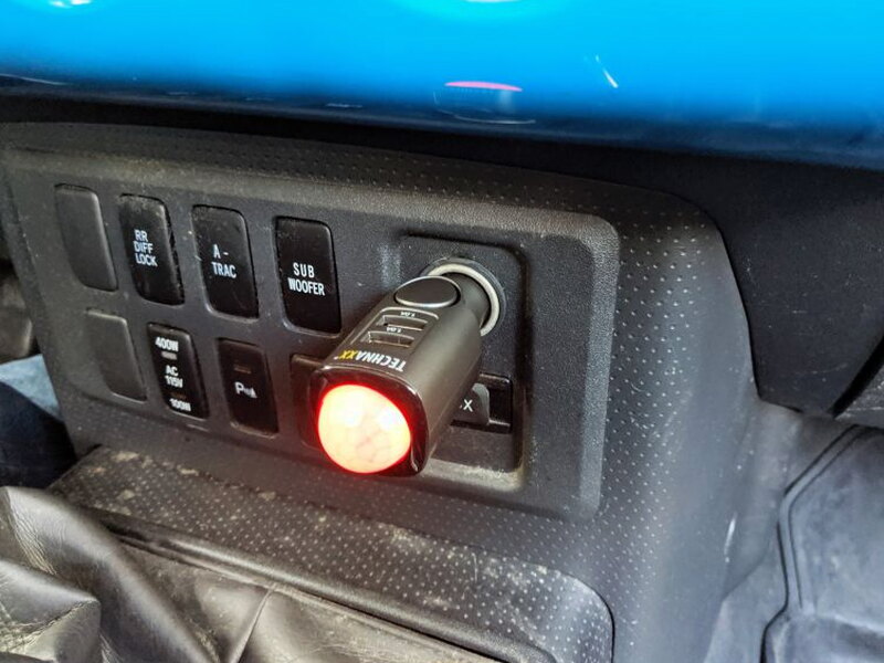 The alarm plugged into the FJ Cruiser dashboard while its red charging light is on.