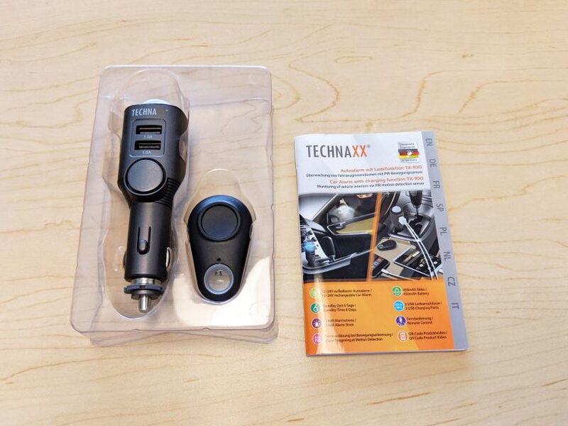 The TX-100, remote, and printed manual are packed in a clear plastic tray.