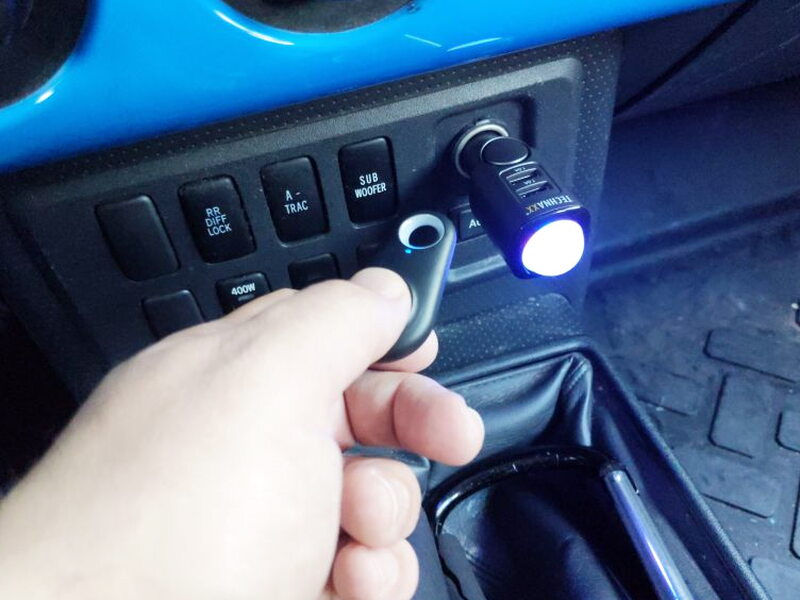 Pairing and arming are done with the remote while the TX-100 is installed in the dash socket.