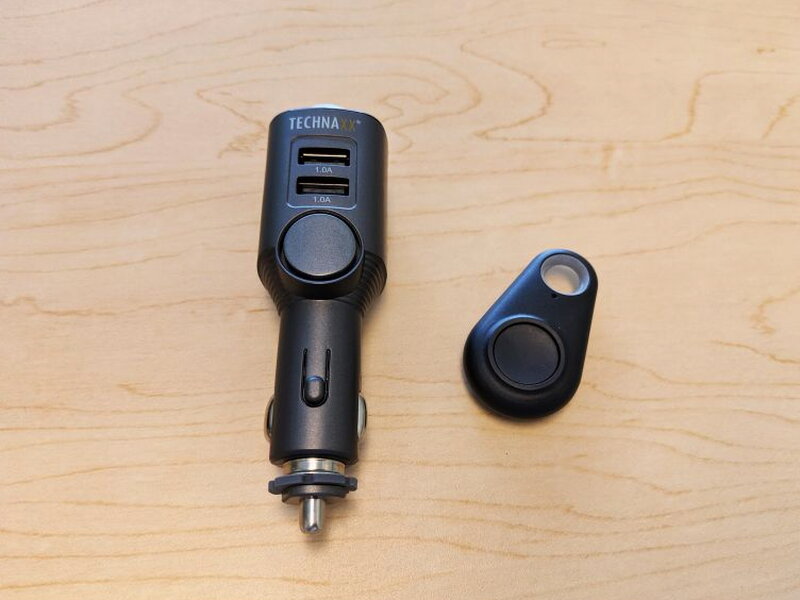 A straight-on view of the gray alarm unit beside the small black remote.