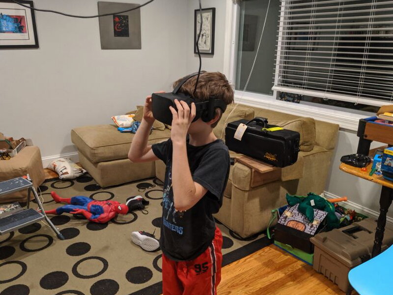 A younger tester wearing the VR headset below the suspended cable system.