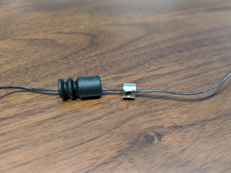 The rubber cover pulled back to expose the cable adjustment nut.