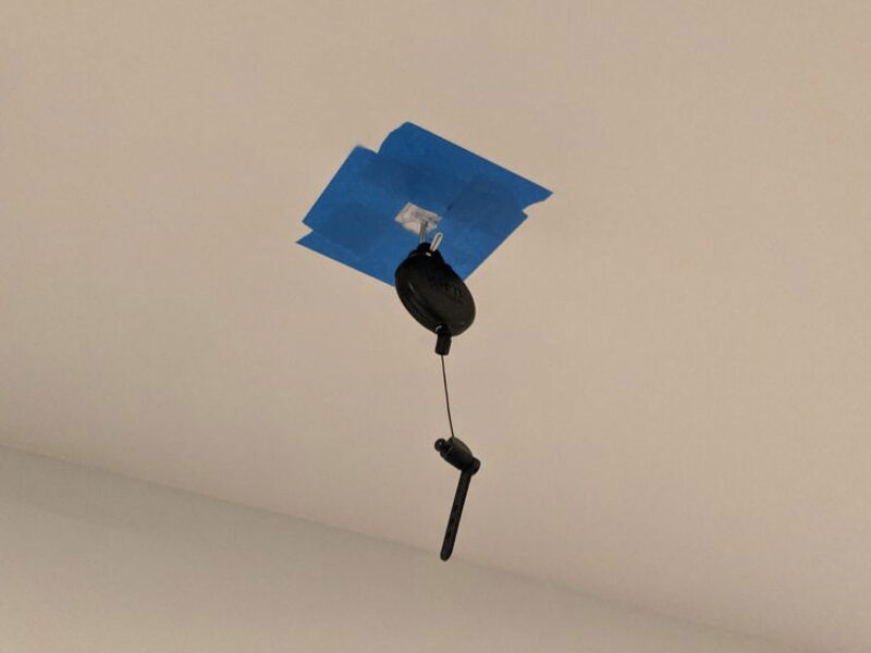 A test pulley temporarily mounted to the ceiling with painter’s tape.
