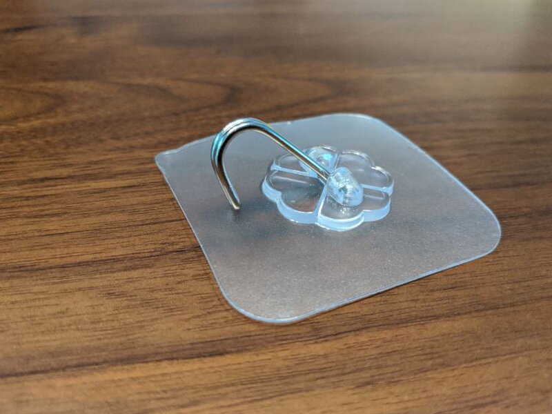 An adhesive ceiling hook mounted on its clear pad.