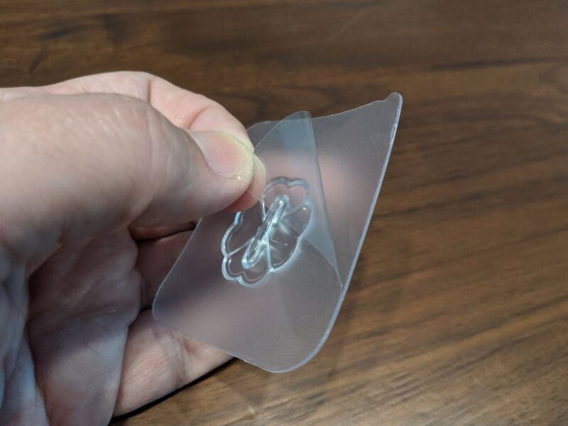 Peeling the backing from an adhesive hook before installation.