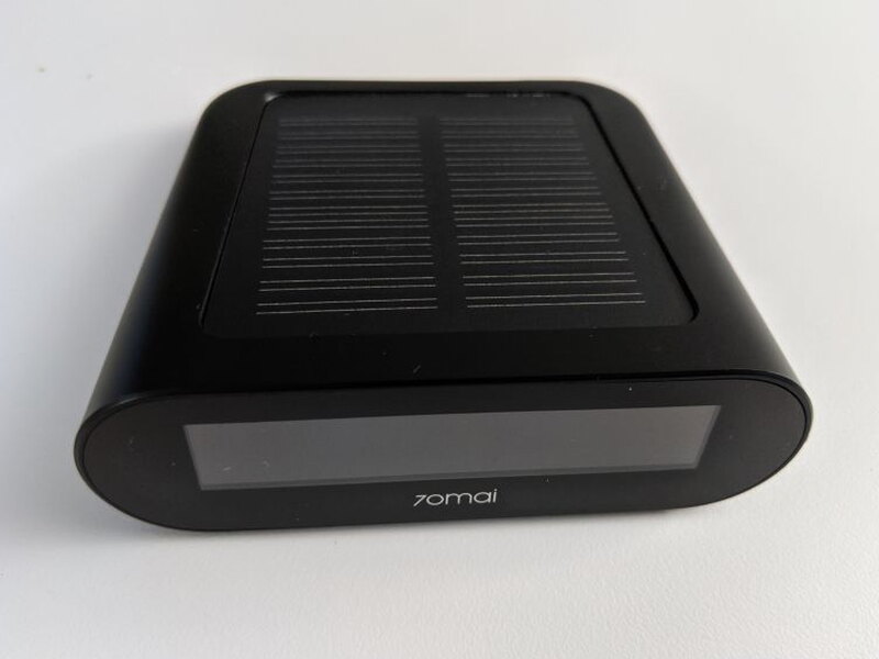 The receiver has a glossy display face and a solar panel built into the top surface.