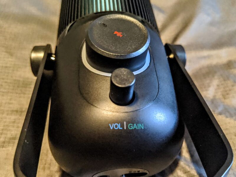 The small volume/gain dial up close, with the mute icon glowing red on the large dial behind it.