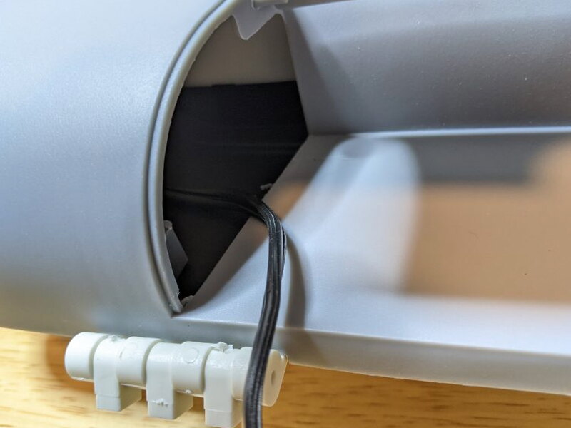 The hard-wired power cord exiting the lid compartment.