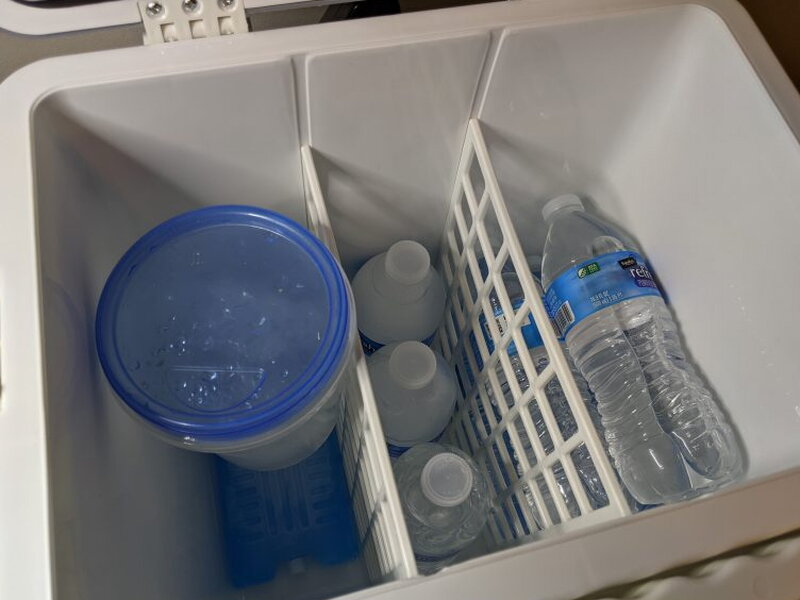 Loaded cooler with bottles, ice packs, and a water container.