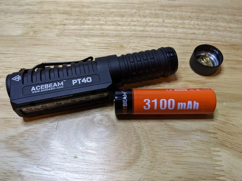 The PT40 opened beside the orange Acebeam 3100 mAh rechargeable battery.